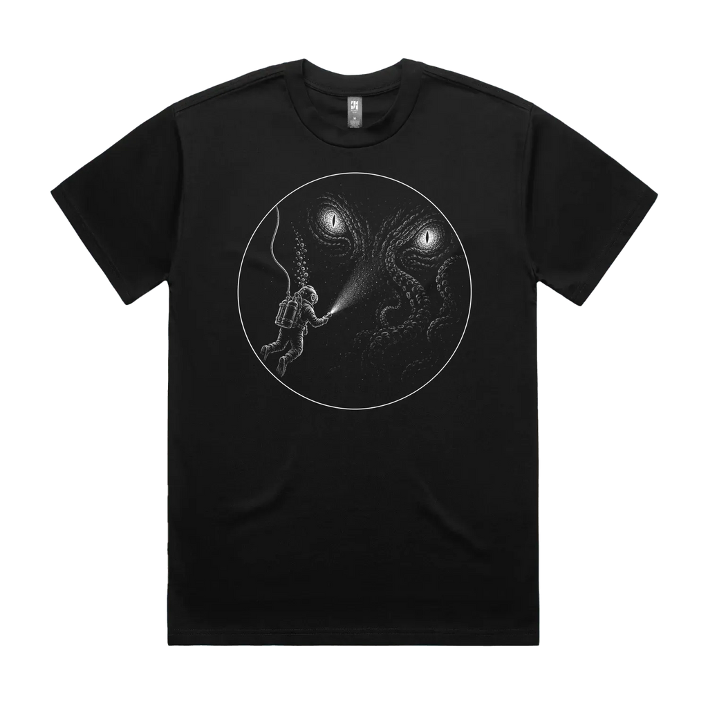 Front mockup of Vestigium XIII luxury 280 GSM heavyweight black t-shirt featuring a solitary deep-sea diver illuminated against an immense leviathan entity, rendered in meticulous stippled textures and razor-sharp fine-line detail printed in monochrome ink.